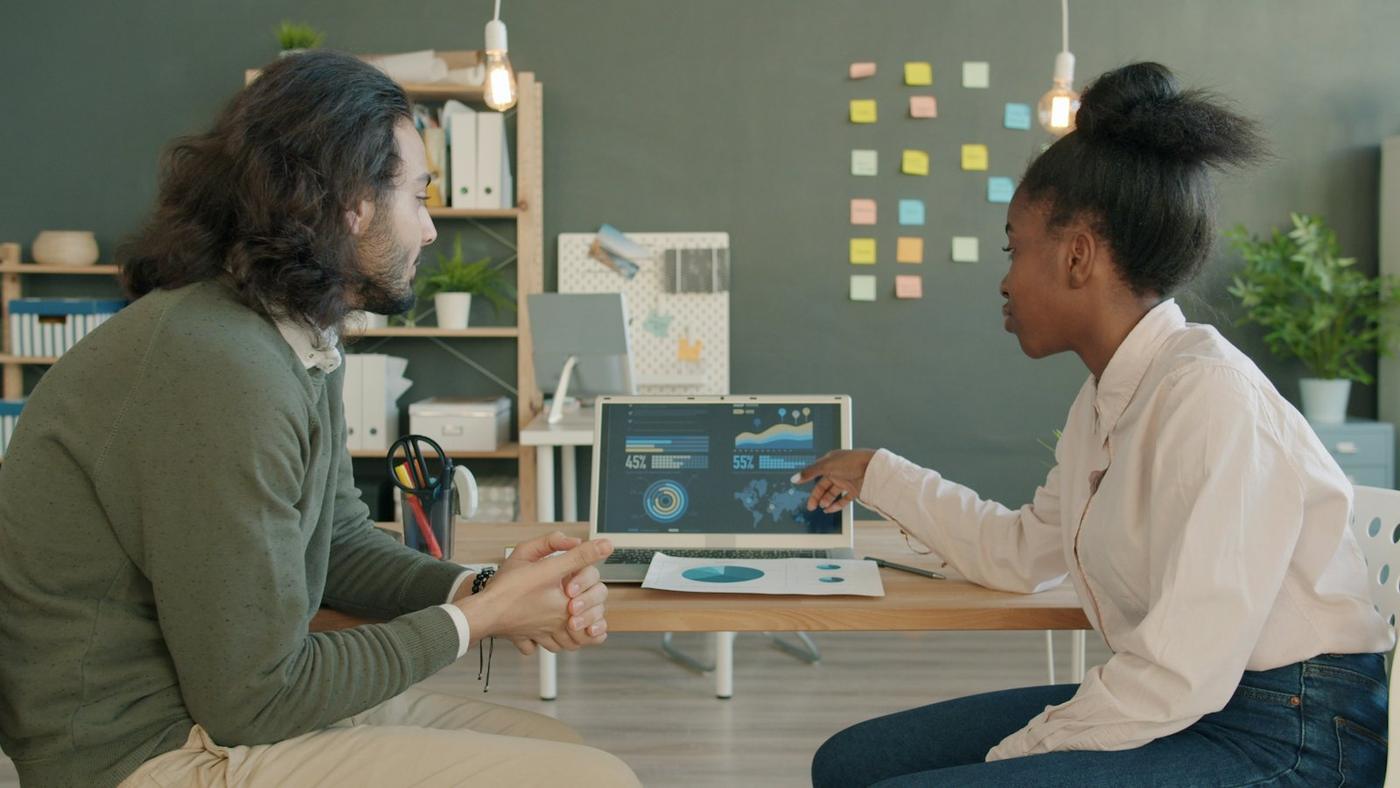 Two colleagues reviewing data on a laptop